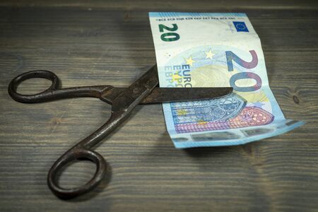 Old vintage scissors cut twenty EUR banknote over rustic wooden background. European Central Bank interest rate cuts conceptの写真素材