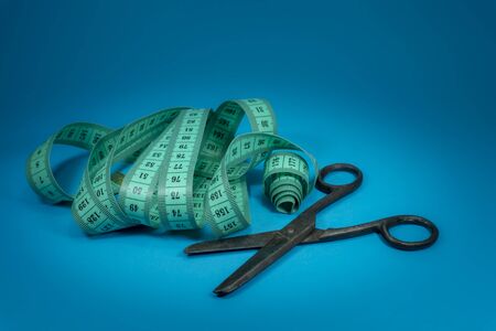 Vintage metal scissors with tape measure on blue background, needlework and tailoring conceptの写真素材