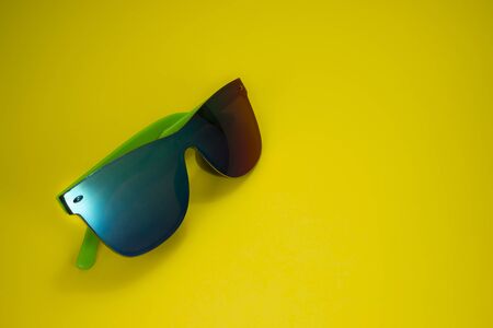 Modern colorful sunglasses on yellow background with copy space for textの写真素材