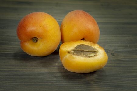 Fresh whole and sliced halved apricots on a rustic wooden table in a close up viewの写真素材