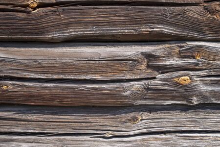 Background texture of old weathered wood cladding on a wall with natural dried planks of cracked and knotty timber in a full frame viewの写真素材