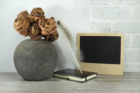 Back to school concept with book, quill pen and chalk board against a white brick wall with free copy spaceの写真素材