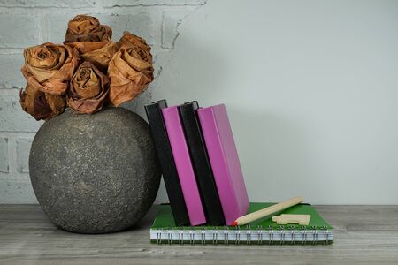 Back to school concept with pile of books and chalk board against a white brick wall with free copy spaceの写真素材