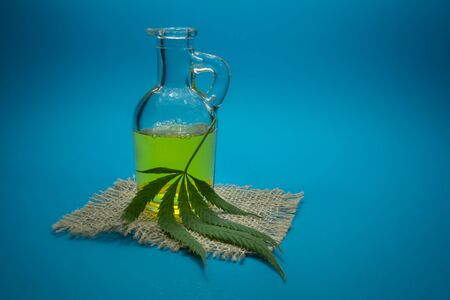 Cannabis leaf and glass decanter on a square of hessian. Cannabis Oil - medical marijuana conceptの写真素材