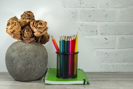 Back to school concept with green spiral ring bound notebook and pencils on the table against a white brick wall with free copy spaceの写真素材