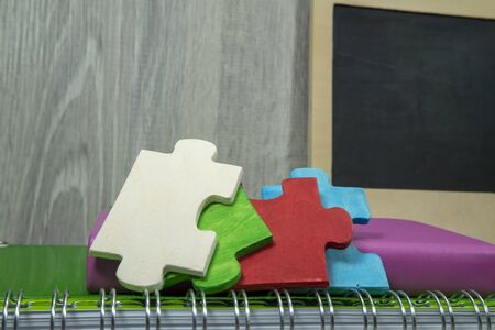 Back to school concept with colorful wooden puzzle pieces, books and chalk board on the table...