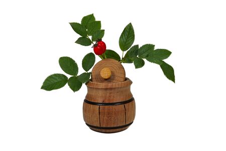 Bright red rose hips with green leaves on small wooden pot isolated on white with copy space rich in Vitamin C and used for medicinal treatmentの写真素材