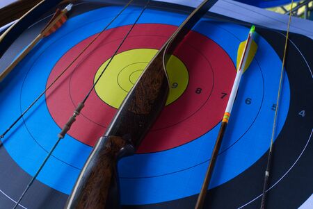Bow and arrow with an archery target in a close up oblique angle view in a concept of goals, skill, sport and precisionの写真素材
