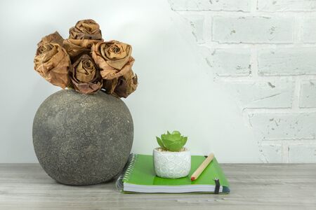 Back to school concept with green spiral ring bound notebook and potted plant on the table against a white brick wall with free copy spaceの写真素材