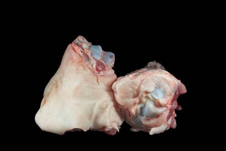 Two raw knuckle or joint bones on black, one with skin covering the bone and copy space aboveの写真素材