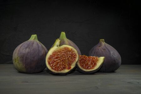 Ripe, purple figs on wooden table with sliced one figの写真素材