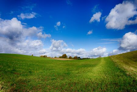 Agricultural landscape with rolling hills blue sky and white cloudsの写真素材