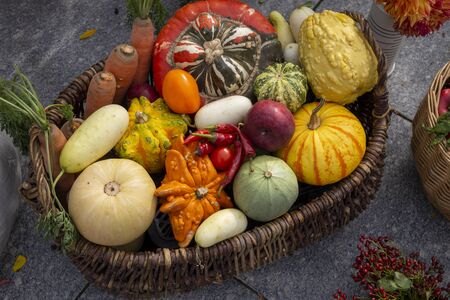 Various colorful pumpkins and vegetables in rustic wicker basket, viewed from above in close-up. Autumn harvest still lifeの写真素材