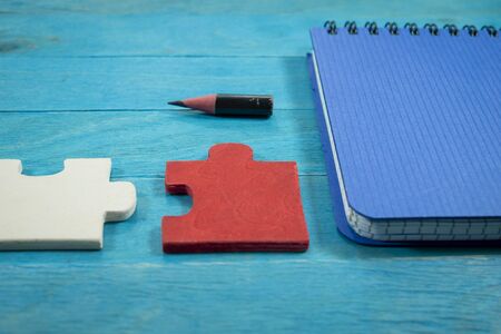 Problem solving and teamwork concept with colorful puzzle pieces in red, white and green on a blue...