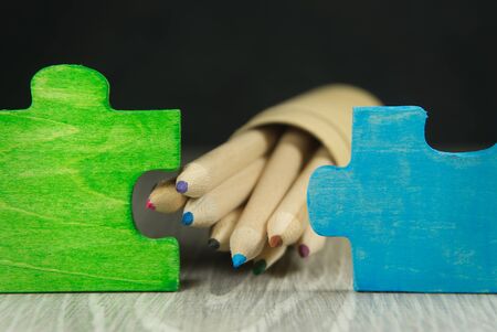 Problem solving and teamwork concept with colorful puzzle pieces in green and blue on a table with a pencils in a low angle viewの写真素材