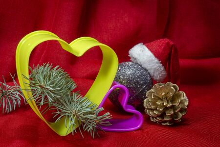 Close-up on Christmas decorations and plastic heart-shaped cookie cutters sitting on red cloth backgroundの写真素材