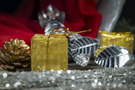 Festive Christmas background with golden gift and cone with a pine branch, colorful red drape and assorted decorationsの写真素材