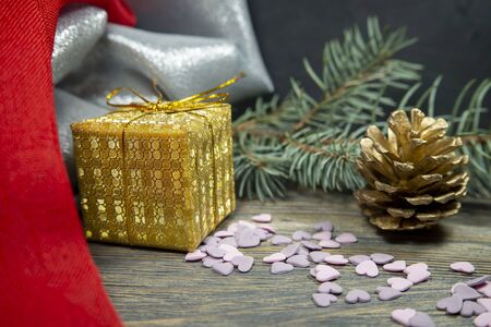 Festive Christmas background with golden gift and cone with a pine branch, colorful red drape and assorted decorationsの写真素材