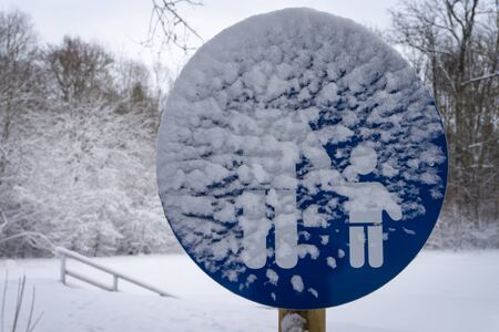Children crossing or school sign obscured by winter snow in a woodland landscape with fresh snowfall conceptual of the seasonsの写真素材
