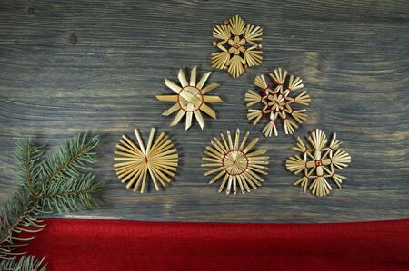 Rustic Christmas still life with handcrafted straw ornaments, pine branches and matching red fabric on a wooden background, eco friendly Christmas toys conceptの写真素材