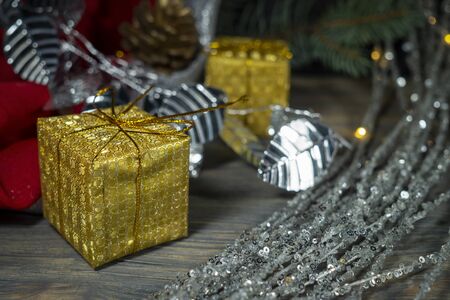 Festive Christmas background with golden gift and cone with a pine branch, colorful red drape and assorted decorationsの写真素材