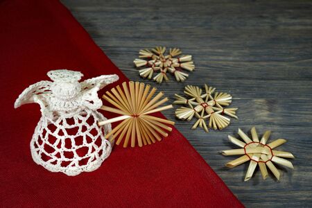 Rustic Christmas still life with handcrafted straw ornaments, a crocheted angel, matching red fabric on a wooden background, eco friendly Christmas toys conceptの写真素材