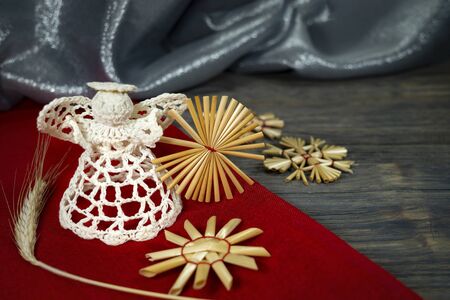 Rustic Christmas still life with handcrafted straw ornaments, a angel of crocheted thread, matching red fabric and ears of golden wheat on a wooden background, eco friendly Christmas toys conceptの写真素材