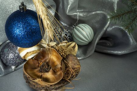 Christmas decorations with cones, fir branch and softly draped silver grey fabric in a seasonal still life to celebrate the holiday seasonの写真素材