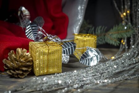 Festive Christmas background with golden gift and cone with a pine branch, colorful red drape and assorted decorationsの写真素材