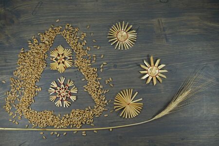 Rustic Christmas background with handicrafts on a textured wood background with an Xmas tree made of seeds, ear of golden wheat and straw snowflakes, eco christmas decorations conceptの写真素材