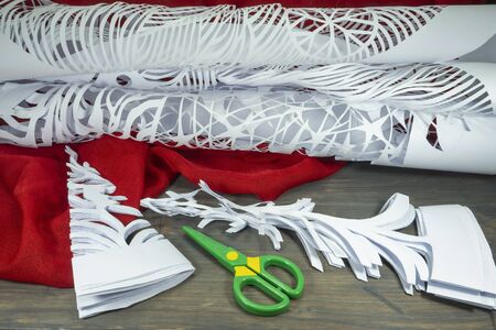 Christmas handicrafts and homemade decorations in a festive background with scissors and paper cutouts of decorative trees and intricate patternsの写真素材