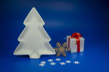 Festive blue Christmas still life with gifts, decorative Christmas tree shape plate and a snowflake decorations with copy space for a holiday greetingの写真素材