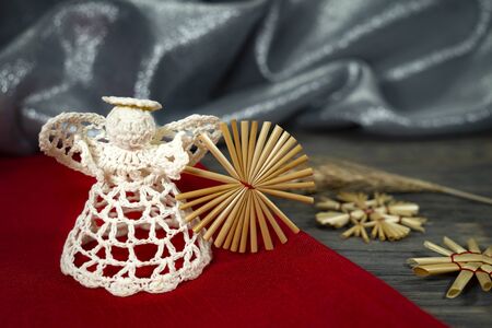 Rustic Christmas still life with handcrafted straw ornaments, a crocheted angel, matching red fabric on a wooden background, eco friendly Christmas toys conceptの写真素材