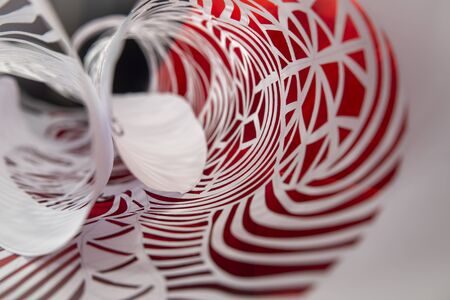 Rolled intricate homemade Christmas decoration cut from white paper in a receding abstract background view with selective focusの写真素材