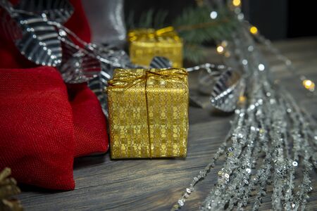 Festive Christmas background with golden gift and cone with a pine branch, colorful red drape and assorted decorationsの写真素材