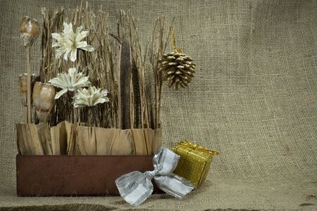 Christmas still life with gold wrapped gift, decorations over a hessian or burlap background with copy space for a seasonal greetingの写真素材