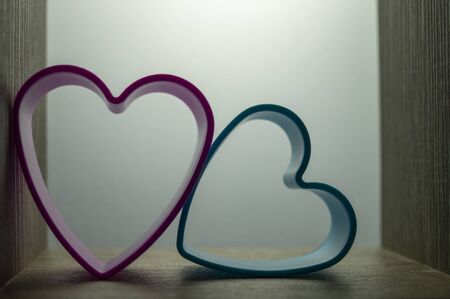 Couple of heart-shaped cookie cutters in white glow, viewed in close-up as love conceptの写真素材