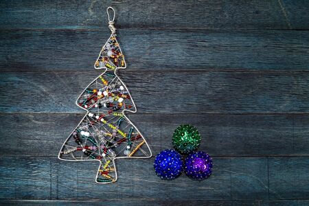 Rustic Christmas decoration on wood with a colorful wire frame Xmas tree and baubles with copy space for a seasonal greetingの写真素材