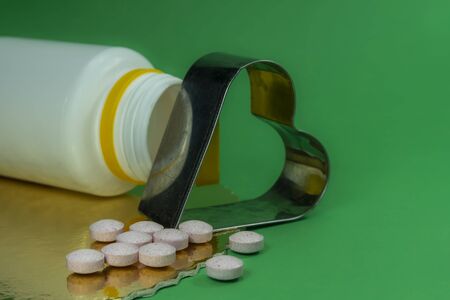 Medical pills and iron heart on a green background. Drug therapy and blood pressure conceptの写真素材