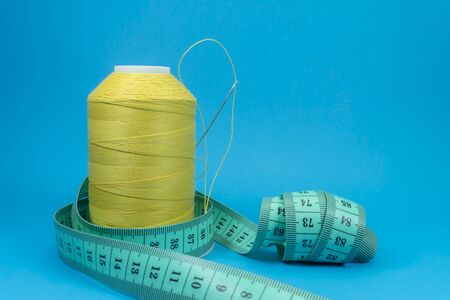 Needlework and tailoring concept - spools of thread and tape measure on blue backgroundの写真素材