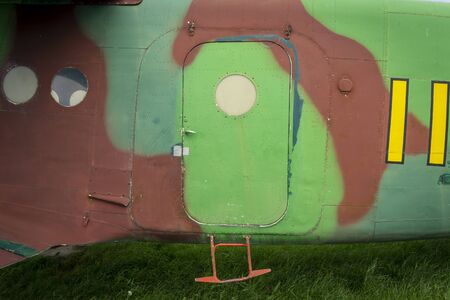 Colorful camouflage colours on a an old vintage plane fuselage with door and small entry steps parked in a grassy fieldの写真素材