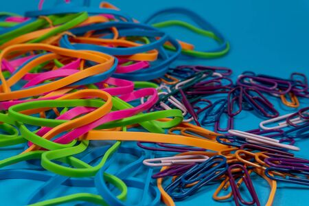 Pile of colorful rubber bands and paper clips over blue backgroundの写真素材