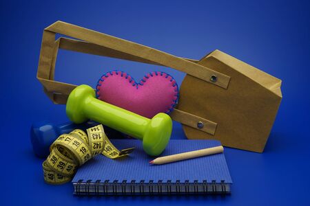 Going shopping for sports diet concept still life with dumbbells, measuring tape and notebook on blue backgroundの写真素材