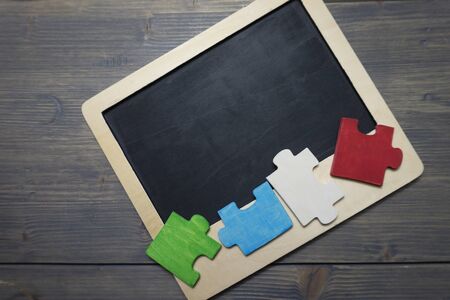 Colorful plywood puzzle pieces in green, blue, white and red on chalk board, problem solving and...