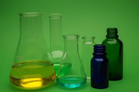 Assorted colorful laboratory glassware over a green background in a conceptual imageの写真素材