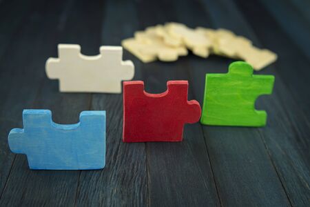 Close-up on pieces of colorful wooden puzzle randomly lying on dark table surface from, viewed from high angleの写真素材