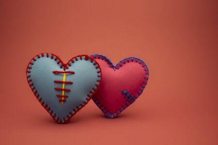 Hand stitched foam sheet blue and pink toy hearts over a red background for romantic, relationship, Valentines Day, broken heart love conceptの写真素材