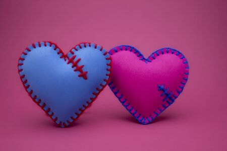 Hand stitched foam sheet blue and pink toy hearts over a pink background for romantic, relationship, Valentines Day, broken heart love conceptの写真素材