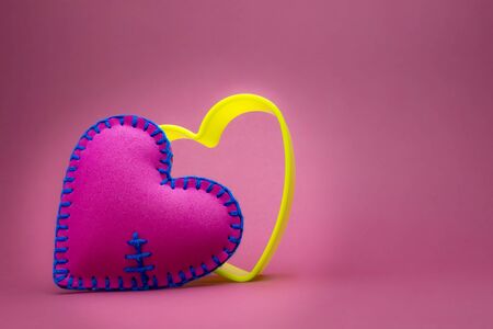Romantic still life with hand sewn textile pink heart and nested colorful hearts shapes on pink with copy space for a message to your sweetheartの写真素材
