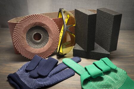 Various grinding tools - sanding belt, clamps, abrasive sponge and flap disc for angle grinder, safety gloves and goggles, renovation, safety and health at work conceptの写真素材